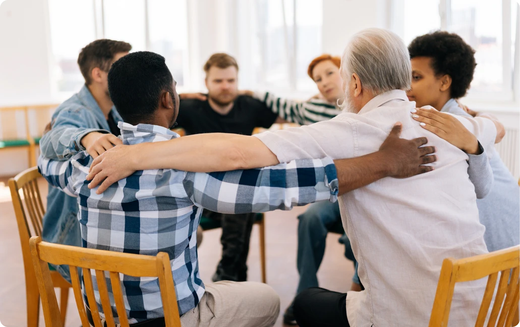 People embracing during group meeting